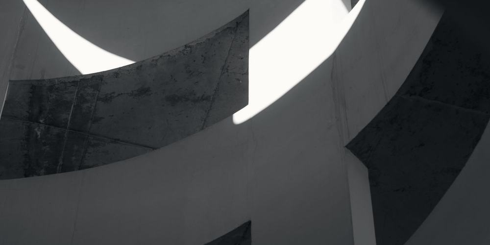 Curved concrete forms meeting in hard light